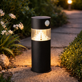 Schwarze zylinderförmige premium solar-gartenleuchte mit warmweißen led-leuchten und bewegungssensor oben