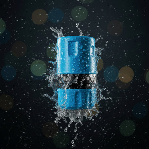 1/2 schlauch schellverbindungsstück aus blauem kunststoff mit schwarzem zentralelement spritzend im wasser vor dunklem hintergrund