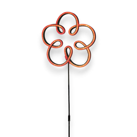 Ein leuchtend orangefarbenes neonblumenlicht mit schwarzem stiel für den außenbereich als gartenstecker