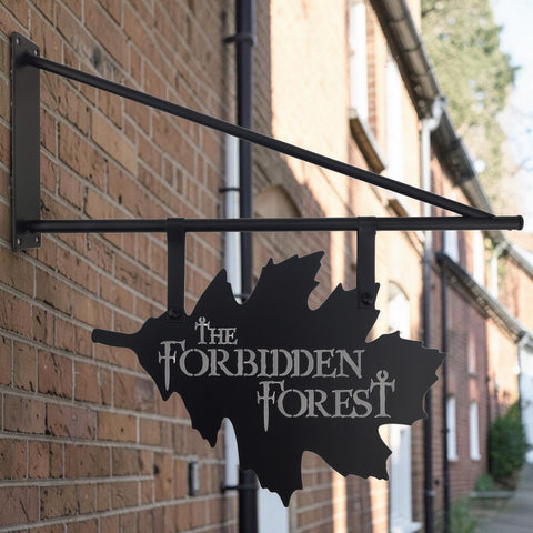 Schwarzes metall-türschild in blattform mit weißer schrift der verbotene wald für wanddekoration