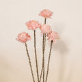 Ein set aus fünf zarten rosa künstlichen dahlien mit texturierten blütenblättern und schlanken braunen stielen