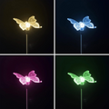 Ein transparenter schmetterlingsförmiger solar-gartenleuchte mit filigranen mustern und wechselnden led-farben gelb blau pink grün