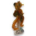 Goldener seepferdchen Fußballfigur mit grünen akzenten aus harz auf texturierter korallenbasis in gloss orange