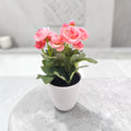 Ein zartes rosa künstliches ranunkel blumenarrangement in einem eleganten weißen keramiktopf 20cm groß