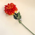 Eine lebendige künstliche dahlie einzeln orange 73cm mit roten und gelben blüten und grünem stiel und blättern
