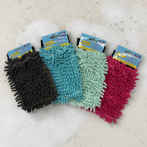 Vier bunte mikrovelour waschhandschuhe in schwarz, teal, mintgrün und magenta auf einer seifigen oberfläche