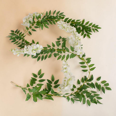 Eine zarte künstliche glyziniengirlande 188cm in weiß mit weiß blühenden blumen und grünen blättern