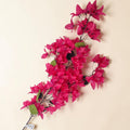 Vibranter fuchsia bougainvillea zweig mit künstlichen blütenblättern und grünen blättern auf dunklen stielen 120 cm